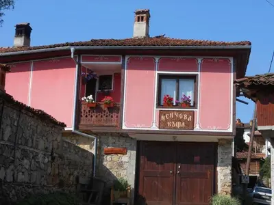 a pink house with a balcony and a window at Nenchova Guest House in Koprivshtitsa