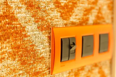 an orange lightswitch on the side of a wall at SCA Sofia City Apartments in Sofia