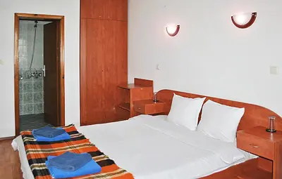 a bedroom with a white bed and a shower at Family hotel Zora in Sofia