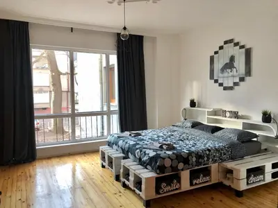 a bedroom with a bed and a large window at Spacious modern vintage flat in the heart of Sofia in Sofia