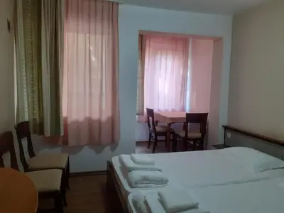 a bedroom with a bed and a table and chairs at Семеен Хотел Хайдутите in Sandanski