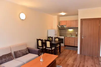 a living room with a couch and a table and a kitchen at Cedar Lodge in Bansko