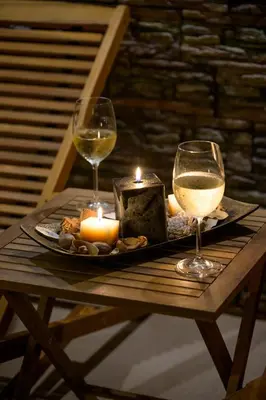 two glasses of wine and candles on a wooden table at Ахат- къща за гости in Kyustendil