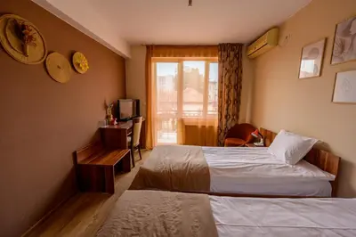 a hotel room with two beds and a window at Ахат- къща за гости in Kyustendil