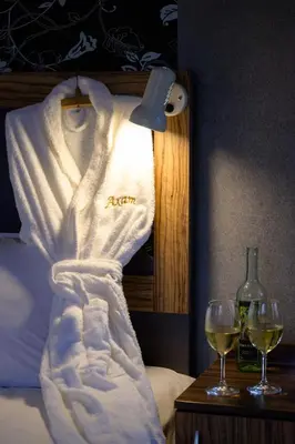 a robe on a bed next to two glasses of wine at Ахат- къща за гости in Kyustendil