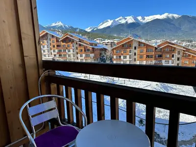 a chair sitting on a balcony with a view of mountains at Luxury apartments in St. John Park in Bansko