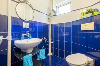 a blue tiled bathroom with a toilet and a sink at FUNKY FRESH place in the heart of Sofia in Sofia