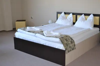 a large bed with white sheets and pillows at Alexander Hotel in Asenovgrad