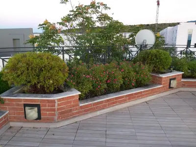 a brick retaining wall with some bushes and flowers at Alexander Hotel in Asenovgrad