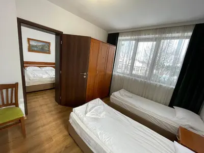 a room with two beds and a chair and a window at Edelweiss Central Hotel in Bansko