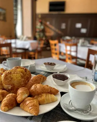 a table topped with plates of pastries and cups of coffee at Park Hotel Panorama in Bansko