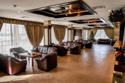 a living room with leather couches and tables and windows at Park Hotel Panorama in Bansko