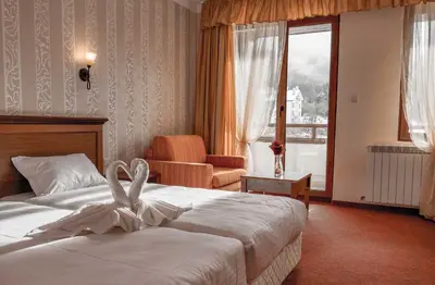 a hotel room with a bed and a chair and a window at Park Hotel Panorama in Bansko