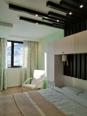 a bedroom with a bed and a white chair at Апартамент Легал in Chepelare
