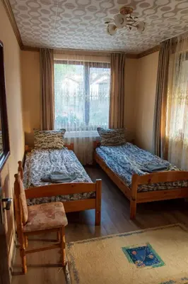 a bedroom with two beds and a chair and a window at Guest House Markovi in Govedartsi