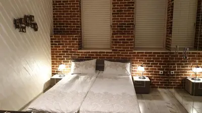 a bedroom with a bed with two night stands and two windows at IFM Boutique studio in Plovdiv