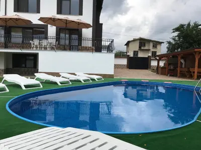 a large swimming pool with chairs and a house at КЪЩА ЗА ГОСТИ ХАРМОНИ in Shiroki Dol