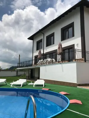 a villa with a swimming pool in front of a house at КЪЩА ЗА ГОСТИ ХАРМОНИ in Shiroki Dol