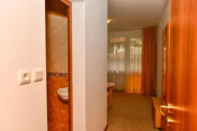 a bathroom with a toilet and a door to a room at Blyan Family Hotel in Chiflik