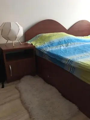 a bed with a wooden headboard and a lamp on a night stand at Ski 'Inn Monastery 3 Ski-to-Door in Pamporovo