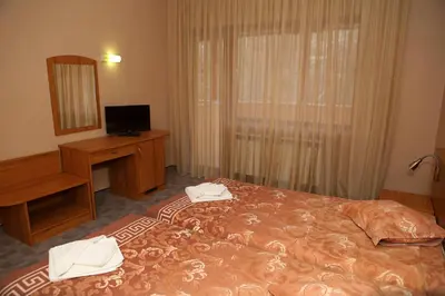 a bedroom with a bed and a desk and a mirror at Family Prim Hotel in Sandanski