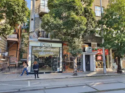 a woman walking past a store on a city street at Apartment Memoir by SofiaSpot - central, metro to airport in Sofia