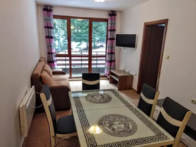 a living room with a table and chairs and a living room at Private Apartments Nevena in Pamporovo