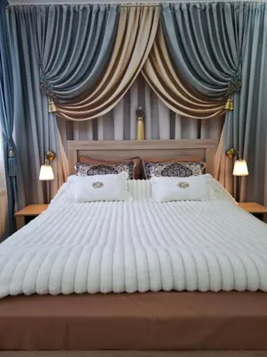 a bedroom with a large white bed with blue drapes at Apartment 15 in Borovets