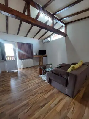 a living room with a couch and a wooden floor at Стаи за гости Върбите in Sapareva Banya