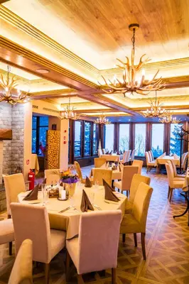 a restaurant with tables and chairs and a chandelier at Hotel and Relax Moreni in Sofia