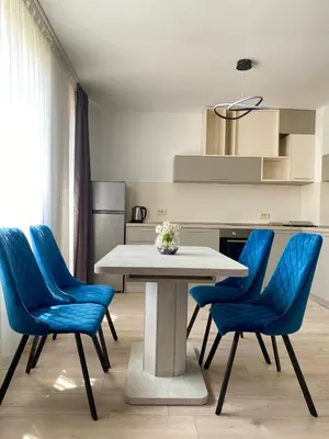 a kitchen with a table and blue chairs at Sapareva Apartments in Sapareva Banya