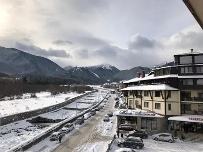 a snowy street with cars parked in the snow at Mountain View Apartment in Bansko