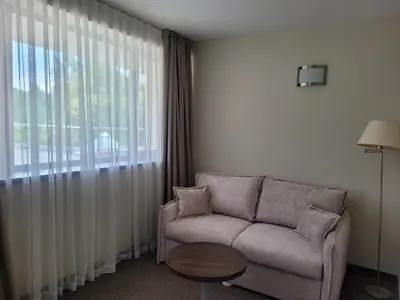 a living room with a couch and a large window at Sana Spa Hotel in Hisarya