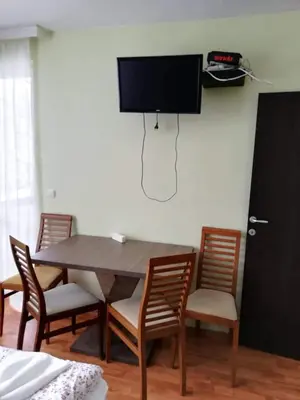 a dining room table with chairs and a tv on a wall at Borovets Apartments, Iglika 2 in Borovets