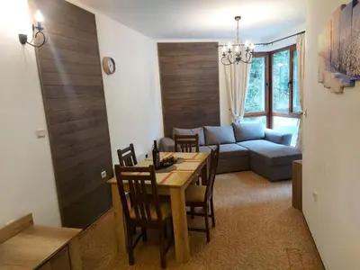 a living room with a table and a couch at Апартамент Winter home Iceberg in Pamporovo