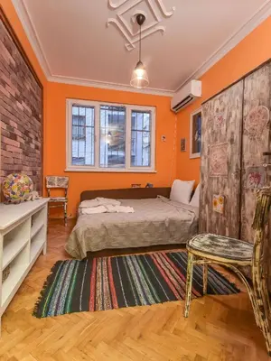a bedroom with orange walls and a bed and a chair at Vintage Spot - Colorful One-Bedroom Apartment by Flat Mаnager in Sofia