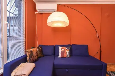 a blue couch in a room with an orange wall at Vintage Spot - Colorful One-Bedroom Apartment by Flat Mаnager in Sofia