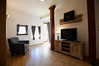a living room with a television and a chair at Dolomiti Apartments in Bansko