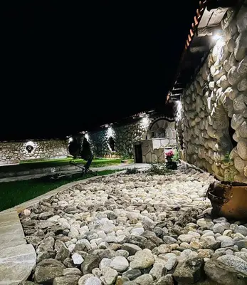 a person walking on a stone path at night at Къща за гости 