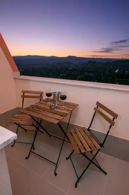 a table with two chairs and wine glasses on a balcony at ГеВе Апартаменти in Sandanski