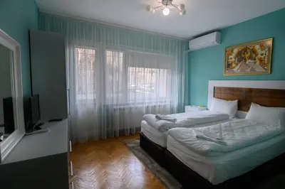 a bedroom with two beds and a flat screen tv at Апартамент за гости Римски терми in Kyustendil