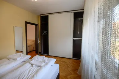 a bedroom with two beds and a large window at Апартамент за гости Римски терми in Kyustendil