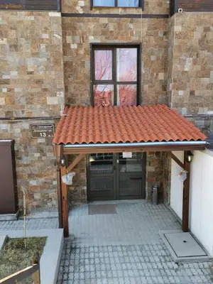 a brick building with a red roof on a patio at Апартаменти Ковачева in Bansko