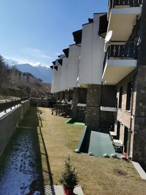 a building with a swimming pool next to a river at Апартаменти Ковачева in Bansko