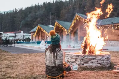 a woman sitting in front of a fire pit at Thermal Camping Velingrad in Velingrad