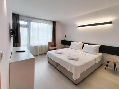 a bedroom with a large white bed and a desk at Guest House 7 in Bansko