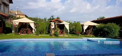 a large swimming pool in a yard with umbrellas at Sharkov Family Hotel in Ognyanovo