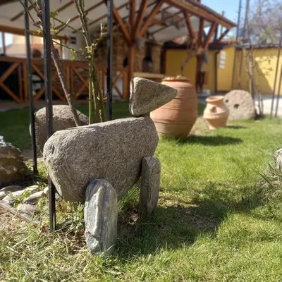 a statue of a stone bear sitting in the grass at Sharkov Family Hotel in Ognyanovo