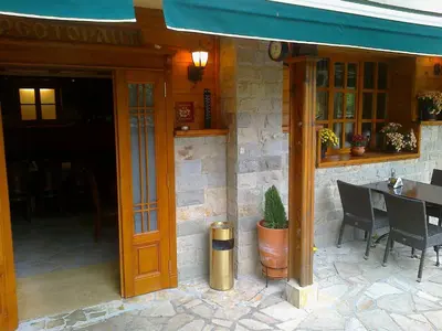 a restaurant with a table and chairs and a blue awning at Family Hotel Pchelina in Rilski Manastir