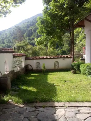 a yard of a house with a mountain in the background at Family Hotel Pchelina in Rilski Manastir